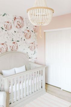 a baby's room with floral wallpaper and a chandelier hanging from the ceiling