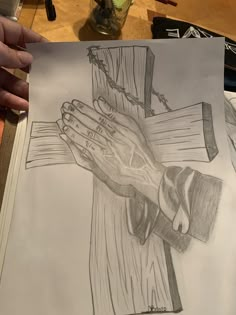 a drawing of a person's hands on top of a cross