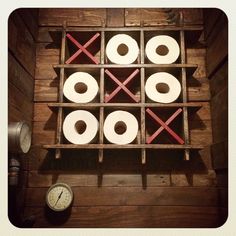 several rolls of toilet paper are arranged in a wooden box on the floor next to a clock