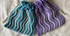 two crocheted pouches sitting on top of a bed next to each other