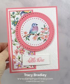 a hand holding up a card that has a bird on it and flowers in the background