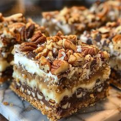 several pieces of dessert sitting on top of a white plate with chocolate and pecans