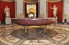 a bathtub in the middle of a room with statues around it