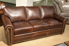 a brown leather couch sitting on top of a carpeted floor