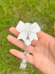 a hand holding a small white bow charm