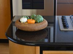 a bowl filled with vegetables sitting on top of a counter next to a microwave oven