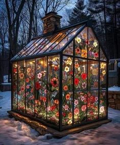 a glass house with flowers painted on it's side in the snow at night