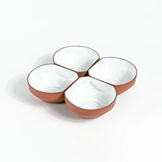 four brown and white bowls sitting on top of each other in front of a white background