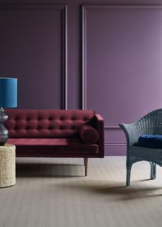 a living room with purple walls and two wicker chairs in front of the couch