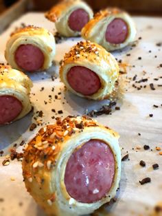 several sausage rolls on a baking sheet with sprinkles and seasoning around them