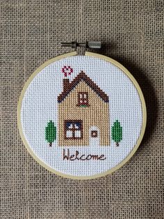 a small cross stitch house with the words welcome on it's front and side