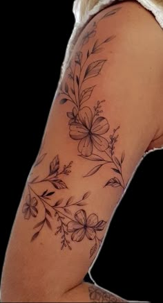 a woman's arm with flowers and leaves tattooed on the back of her shoulder