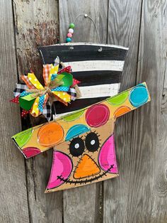 two colorful bags are hanging on the side of a wooden fence, decorated with bows