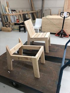 two wooden chairs sitting next to each other on top of a piece of plywood