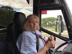 an older woman sitting in the driver's seat of a bus looking out the window