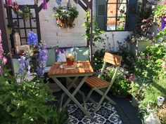 an outdoor table and chairs in the middle of a garden with potted plants on either side