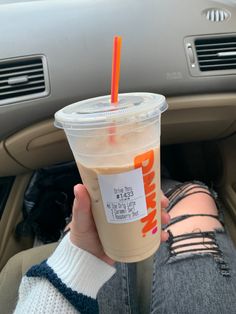 a person holding up a drink in their hand while sitting in the backseat of a car