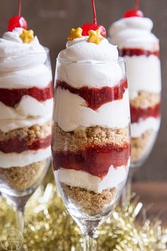 three glasses filled with dessert sitting on top of a table next to a christmas tree