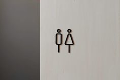 two wooden figures are standing next to each other on a white wall and one is holding a black object