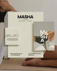 a woman sitting on top of a table next to a white box with the words masha printed on it