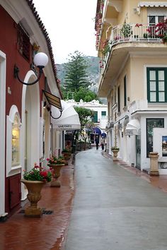 an empty street with potted plants and flowers on the sidewalk in front of buildings