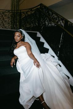 a woman in a wedding dress is walking down the stairs