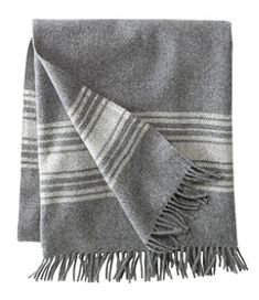 two gray and white blankets folded on top of each other, one with fringes