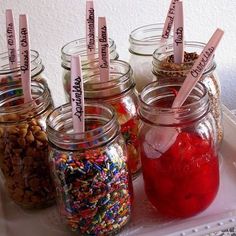 several jars filled with different types of confetti and sprinkles on a tray