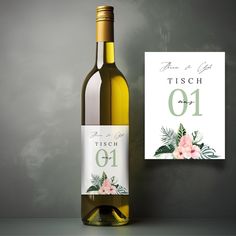 a bottle of white wine next to a greeting card on a gray background with pink flowers