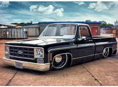 an old black pickup truck parked on the street