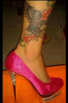 a woman's foot with tattoos on it and pink shoes in the foreground