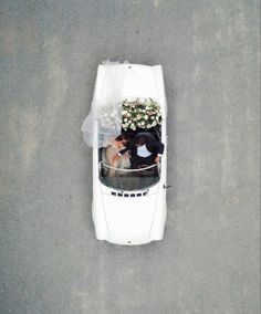 an overhead view of a car with a bride and groom sitting in the back seat