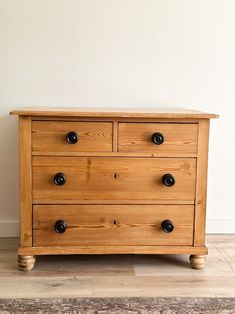 a wooden dresser sitting on top of a hard wood floor next to a white wall