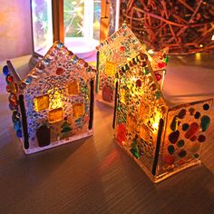 two glass houses sitting on top of a wooden table