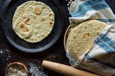 two pita breads sitting on top of a pan next to a wooden spoon