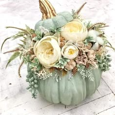 a green pumpkin decorated with white flowers and greenery