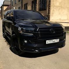 a black suv is parked on the side of the road in front of some buildings