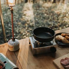 an outdoor table with food on it and a stove top burner in the foreground