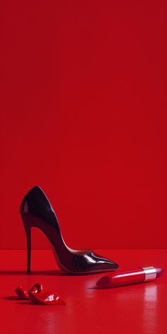 a pair of high heeled shoes next to a pen on a red surface with the background painted bright red