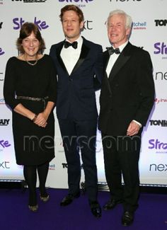 three people standing next to each other on a purple carpet