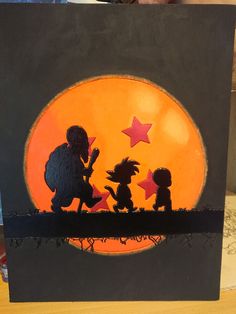 the silhouettes of two children are sitting in front of an orange moon