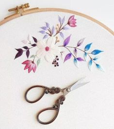 a pair of scissors sitting on top of a table next to a flower embroidery pattern