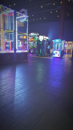 there are many vending machines on the floor in this room, all lit up