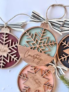 three wooden ornaments are hanging from strings on the wall, one is decorated with snowflakes and the other has an ornament that says country