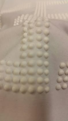 an up close shot of some white balls on a bed sheet that is made out of fabric