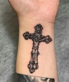 a tattoo on the wrist of a person with a cross