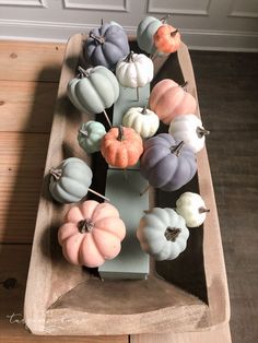 small pumpkins are arranged on a wooden tray in the shape of a boat for display