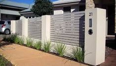 a car parked in front of a house next to a tall white fence with vertical slats on it