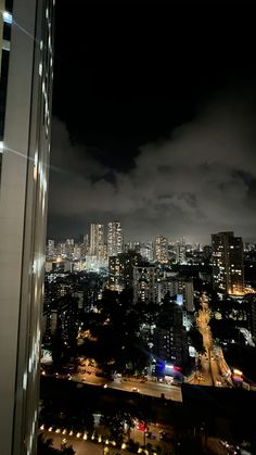 the city is lit up at night with clouds in the sky and buildings on either side