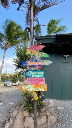 a pole with many signs on it in front of a building and some palm trees